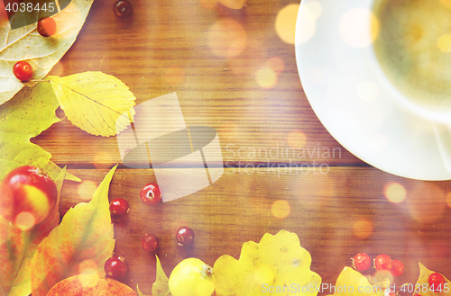 Image of close up of coffee cup on table with autumn leaves