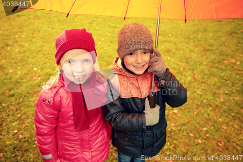 Image of happy boy and girl with umbrella in autumn park