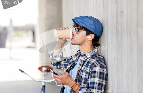 Image of man with earphones and smartphone drinking coffee