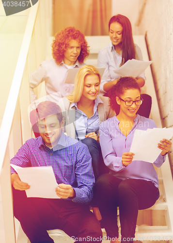 Image of team with papers and take away coffee on staircase