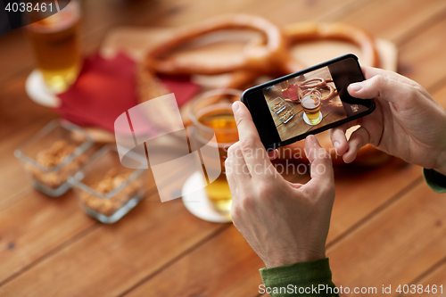 Image of close up of hands with smartphone picturing beer