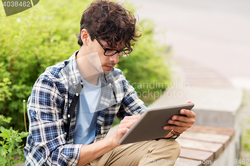 Image of man with tablet pc sitting on city street bench