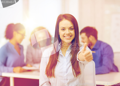 Image of smiling young businesswoman showing thumbs up