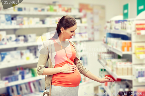 Image of happy pregnant woman choosing medicine at pharmacy