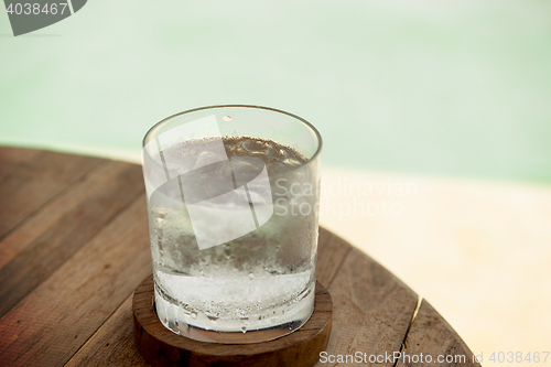 Image of glass of water with ice cubes on table at beach