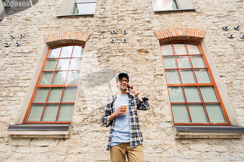 Image of man with smartphone drinking coffee on city street