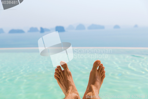 Image of closeup of male feet over sea and sky on beach