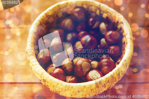 Image of close up of chestnuts in basket on wooden table