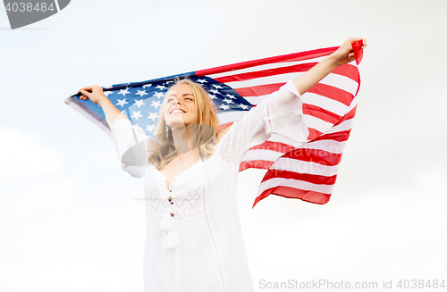 Image of happy young woman with american flag outdoors