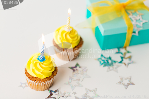 Image of birthday cupcakes with burning candles and present