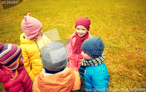Image of happy children standing in circle at autumn park