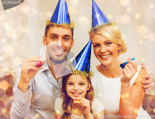 Image of smiling family in blue hats blowing favor horns