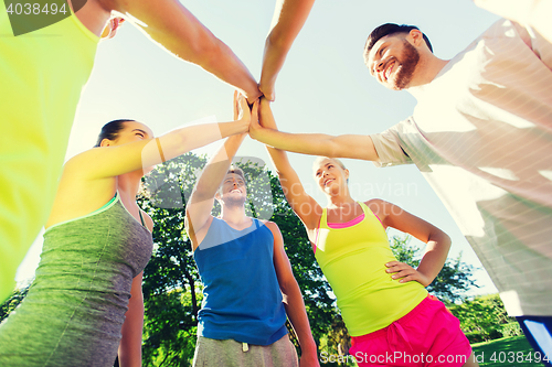 Image of group of happy friends making high five outdoors