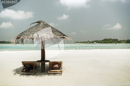 Image of palapa and sunbeds by sea on maldives beach