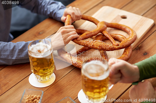 Image of close up of men drinking beer with pretzels at pub