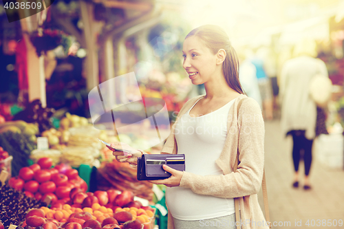 Image of pregnant woman with wallet buying food at market