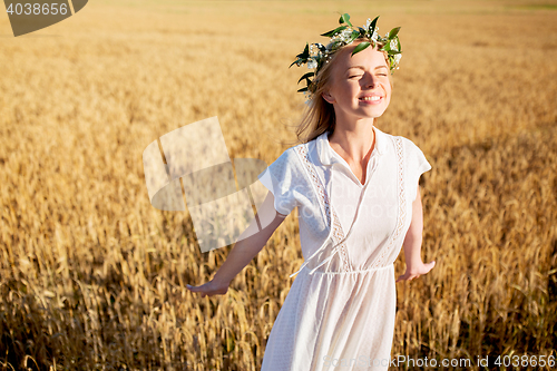 Image of happy young woman in flower wreath on cereal field