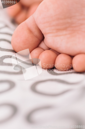 Image of Barefoot baby on bedspread