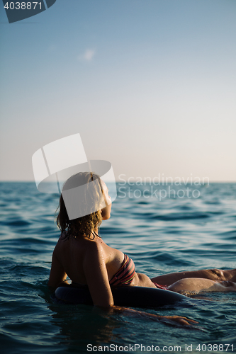 Image of Back view of relaxing woman floating on inflatable ring