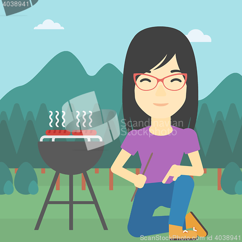 Image of Woman cooking meat on barbecue.