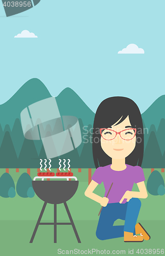 Image of Woman cooking meat on barbecue.