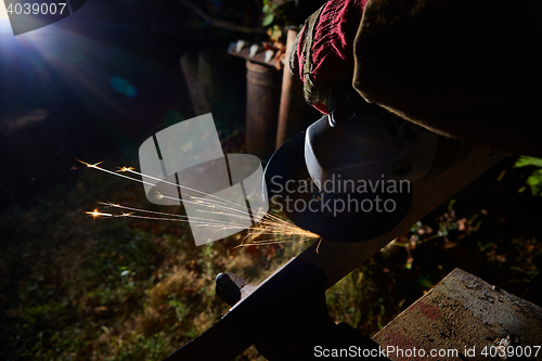 Image of Worker cutting metal with grinder. Sparks while grinding iron