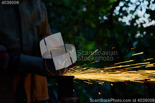 Image of Worker cutting metal with grinder. Sparks while grinding iron