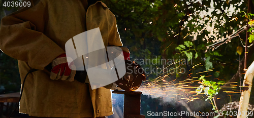 Image of Worker cutting metal with grinder. Sparks while grinding iron