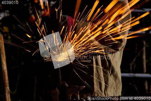 Image of Worker cutting metal with grinder. Sparks while grinding iron