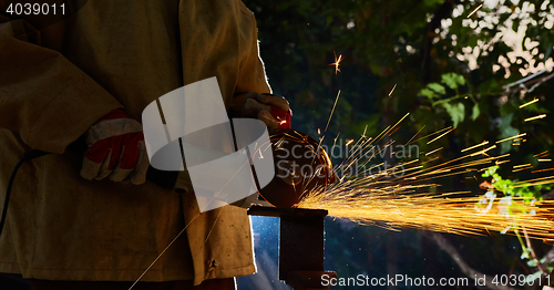 Image of Worker cutting metal with grinder. Sparks while grinding iron