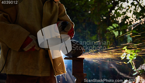 Image of Worker cutting metal with grinder. Sparks while grinding iron