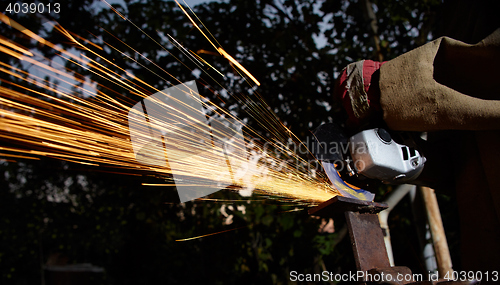 Image of Worker cutting metal with grinder. Sparks while grinding iron