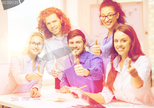 Image of creative team with papers showing thumbs up