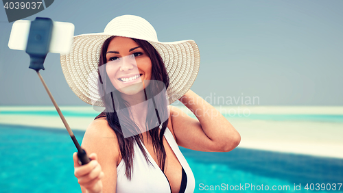 Image of smiling young woman taking selfie with smartphone