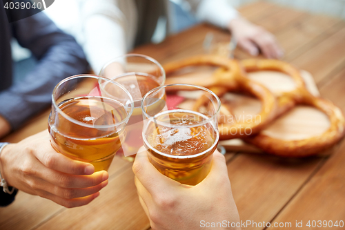 Image of close up of hands clinking beer at bar or pub