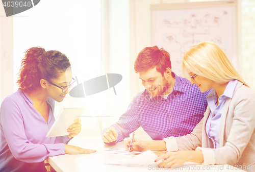 Image of smiling team with table pc and papers working