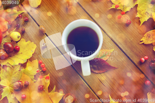 Image of close up of tea cup on table with autumn leaves