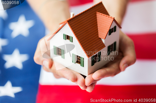 Image of close up of hands holding house over american flag