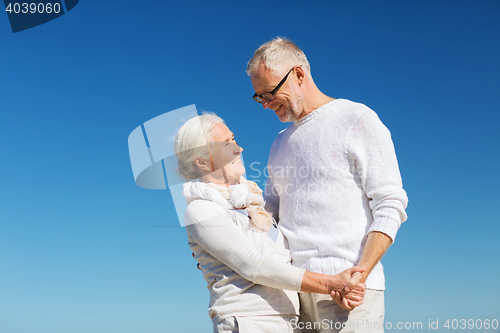 Image of happy senior couple holding hands on summer beach