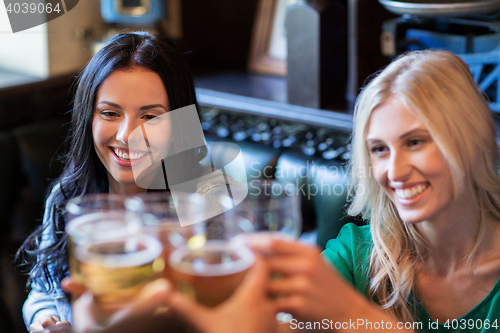 Image of happy female friends drinking beer at bar or pub