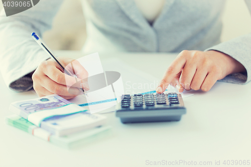 Image of close up of hands counting money with calculator