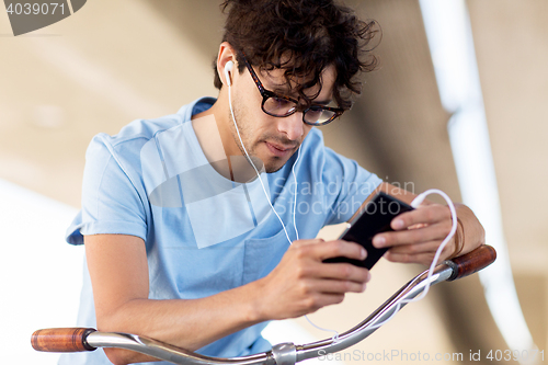 Image of man with smartphone and earphones on bicycle