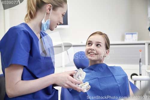 Image of happy dentist showing jaw model to patient girl