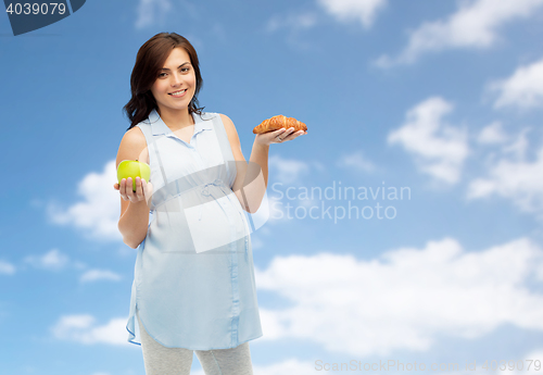 Image of happy pregnant woman with apple and croissant