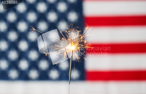 Image of close up of sparkler burning over american flag