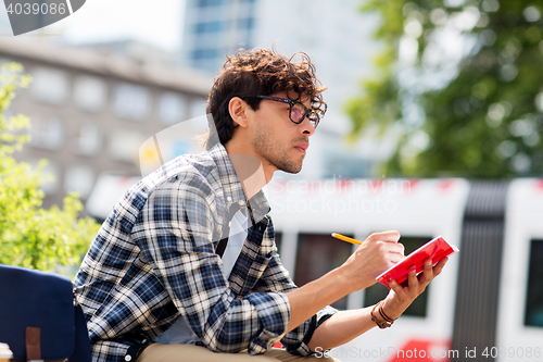 Image of man with notebook or diary writing on city street