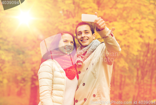 Image of smiling couple hugging in autumn park