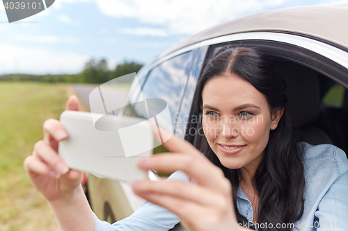 Image of happy young woman driving in car with smartphone