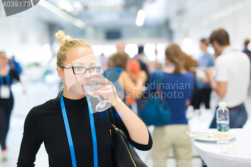 Image of Business woman drinking glass of water during break at business conference.