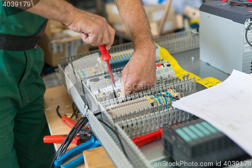 Image of Electrician assembling industrial electric cabinet.